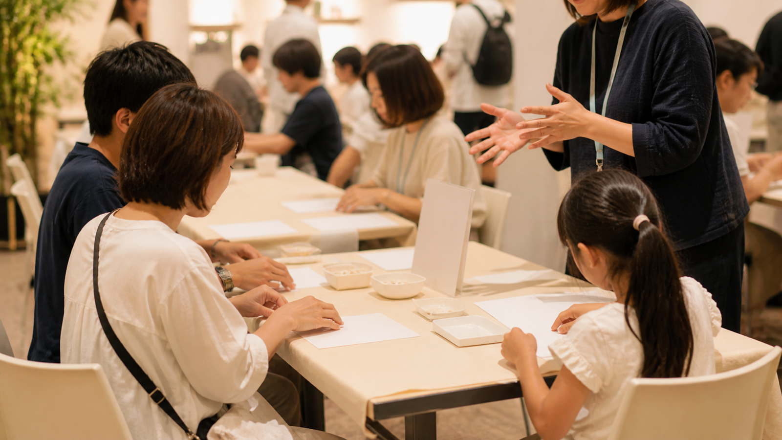 イベント会場の体験コーナーで工作を楽しむ親子とスタッフ