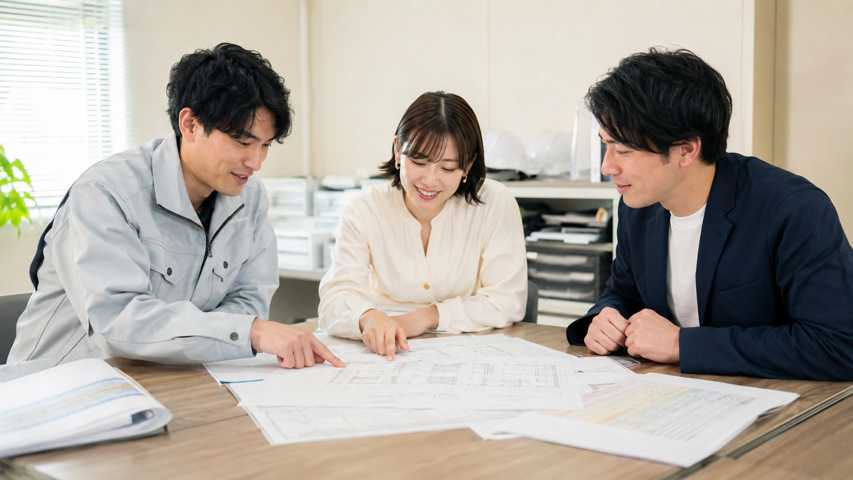 図面と書類を囲んで打ち合わせをする3人